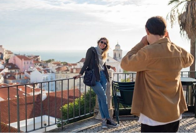 Turistas haciéndose fotos en un mirador con un pueblo al fondo.