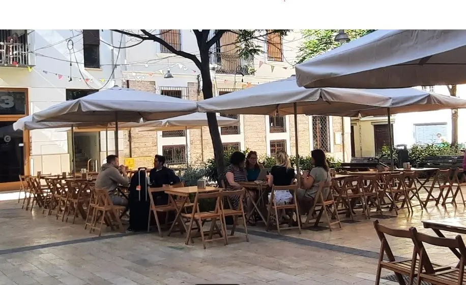 Turistas sentados en la terraza de bar en una plaza de Valencia