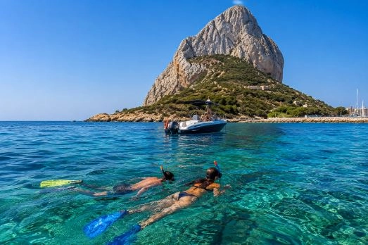 Dos turistas practicando snorkel junto al Peñón de Ifach en Calpe